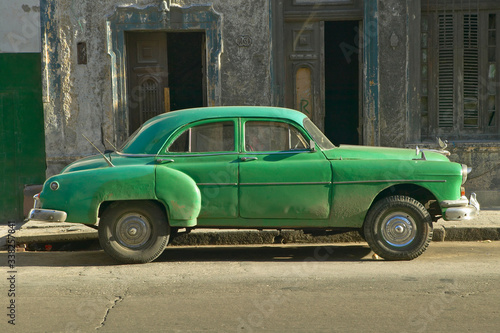 An old green car sitting in front of old building in Old Havana, Cuba