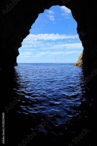 The view from inside a sea cave on the Coromandel Peninsula, New Zealand. A tour boat is just visible in the far distance