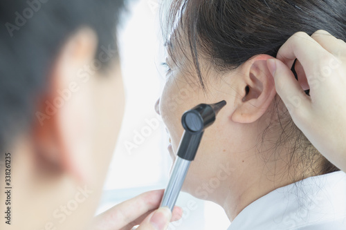 Asian doctor examining patient's ear