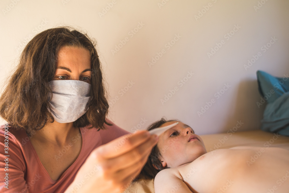 A woman in a protective mask measures the temperature of the child.