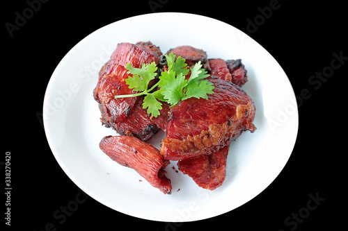 Scorched fried salted meat topping with coriander on white plate.