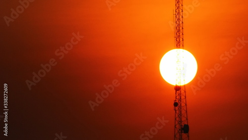 the telacommunecation pole with sunset sky background. blured  silhouette electric workers working on high ground with safety uniform. photo