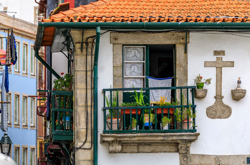 Shabby facades and terracotta roofs of Portuguese houses with flower pots in the balconies of old town Porto, Portugal