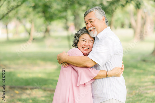 Happy smile senior Asian couple enjoying quality time together and holding each other in the park. © interstid