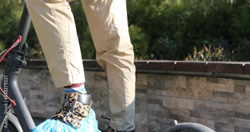 A stylish woman wearing mask and gloves to defened her from coronavirus. Using electric scooter in city and park to be in safe.