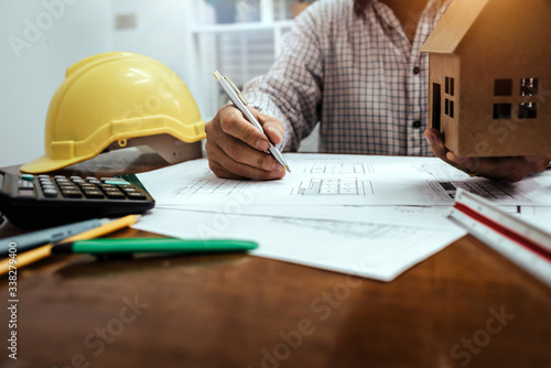 Male engineer working with house blueprint and analysis architectural plan on desk.