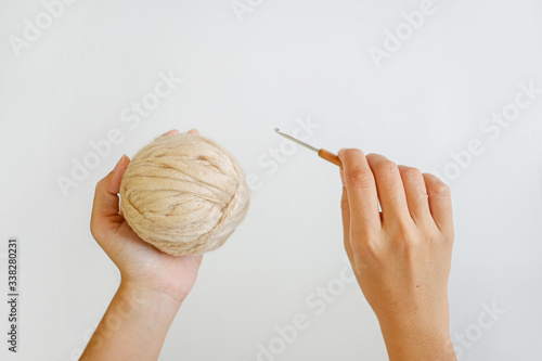 Yarn ball and crochet hook in hand on white background