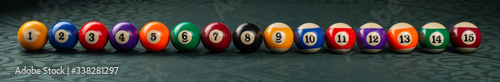 Billiard balls arranged in a row close-up on a green backgound. Wide frame.