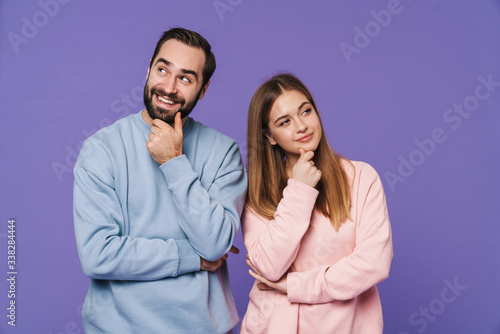 Thinking loving couple isolated over purple background.