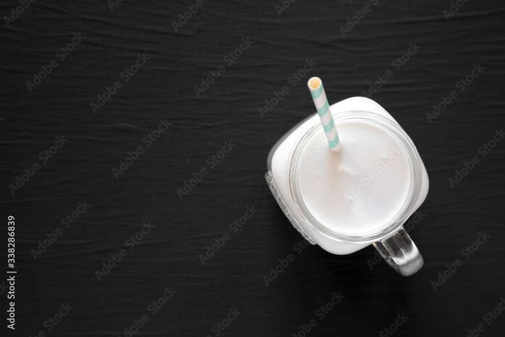 Coconut milk in a glass jar on a black background, top view. Flat lay, overhead, from above. Copy space. Coconut milk in a glass jar on a black background, top view. Flat lay, overhead, from above. Copy space.