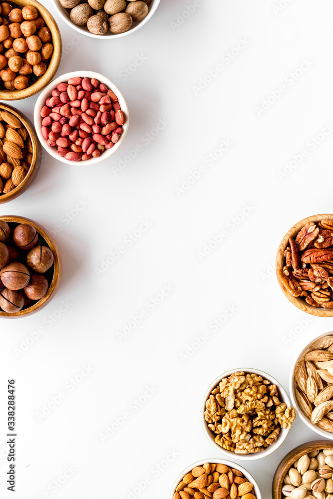 Nuts set in bowls on white background top-down frame copy space Nuts set in bowls on white background top-down frame copy space
