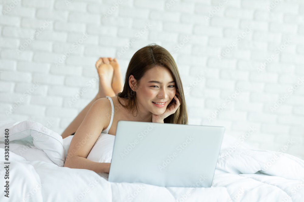 Beautiful Attractive Asian young woman lying on bed and using computer laptop for using social media and shopping online relax in cozy bedroom in holiday,Lifestyle in home Concept Beautiful Attractive Asian young woman lying on bed and using computer laptop for using social media and shopping online relax in cozy bedroom in holiday,Lifestyle in home Concept