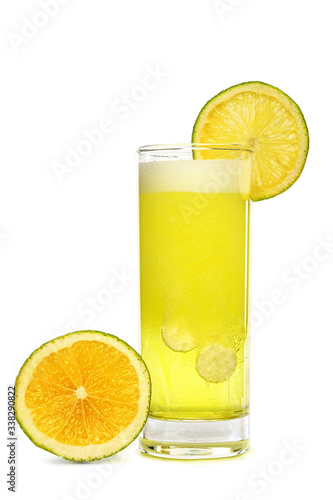 Effervescent soluble tablet pills with Vitamin C in glass of water with sparkling fizzy bubbles trail and Orange fruits on white background