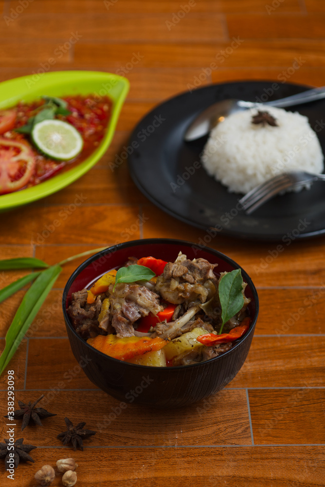 traditional indonesian duck soup on a black bowl over wooden background. traditional indonesian duck soup on a black bowl over wooden background.