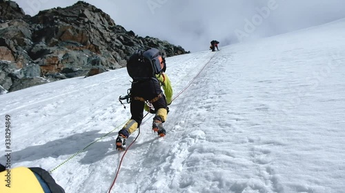Bunch of mountaineers climbs or alpinists to the top of a snow-capped mountain
