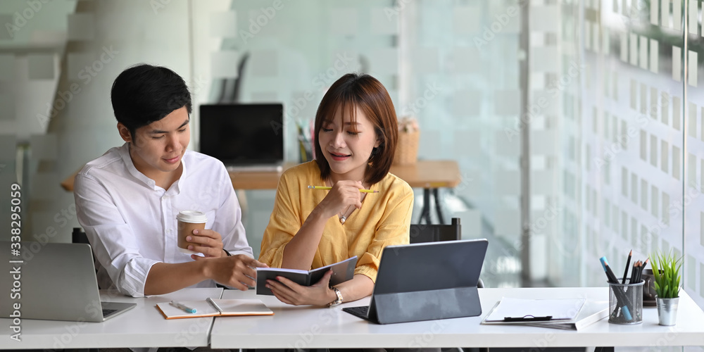 Photo of business consulting team working together with computer tablet while sitting at the long working desk over modern office as background. Photo of business consulting team working together with computer tablet while sitting at the long working desk over modern office as background.