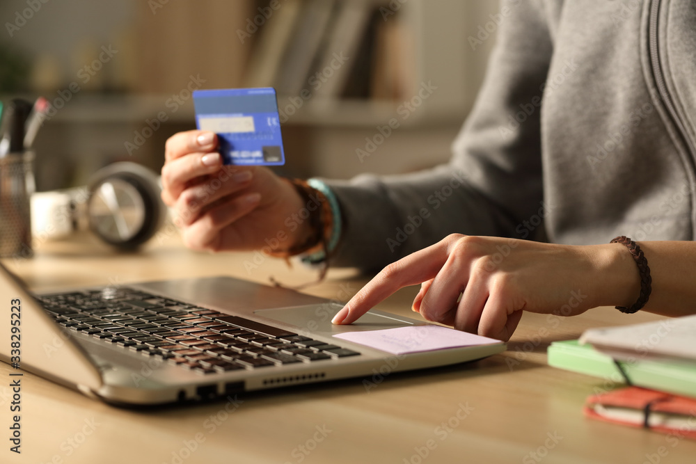 © PheelingsMedia - Student hands paying with credit card on laptop at night