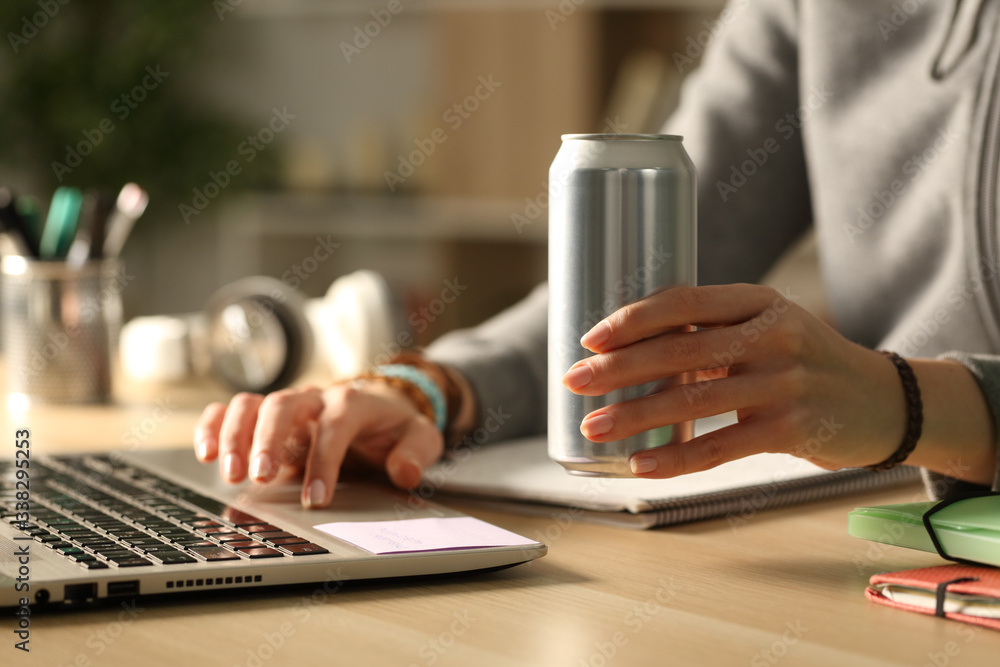 © PheelingsMedia - Student hands holding energy drink can at night studying