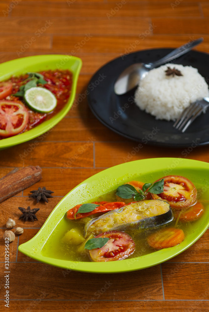 traditional indonesian catfish soup on a green plate over wooden background.