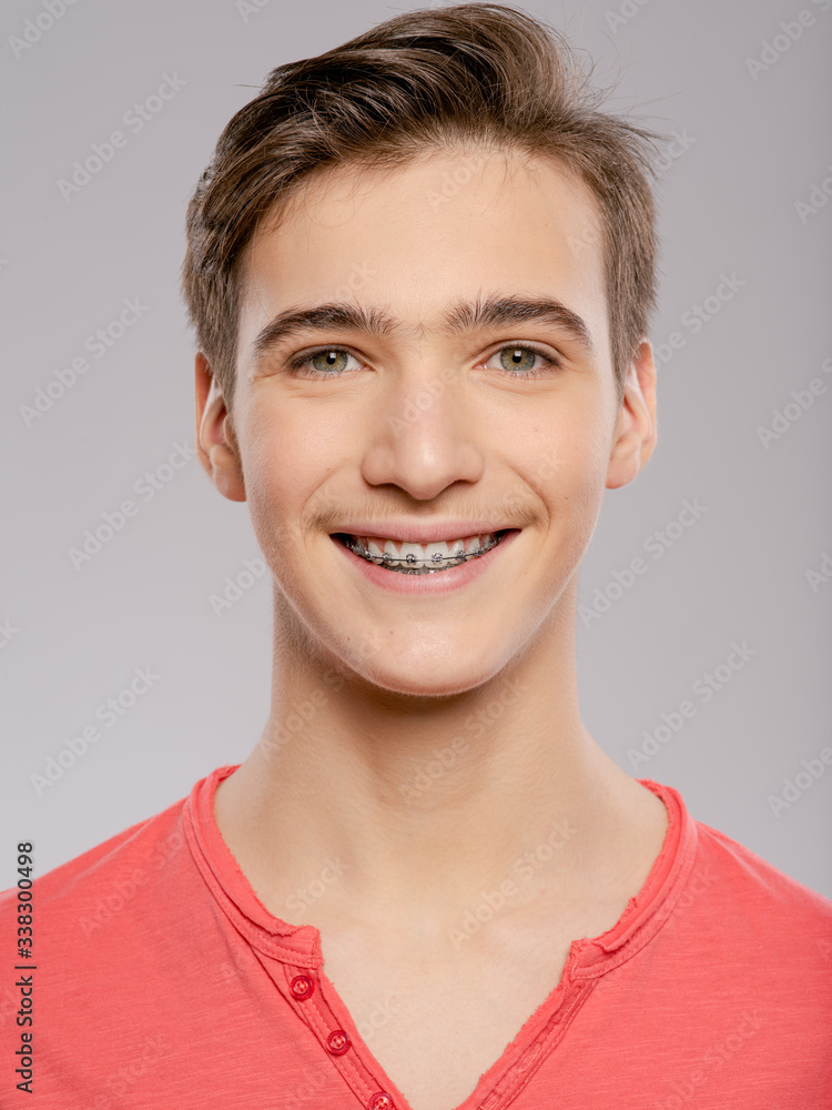 Smiling teen boy with braces on his teeth. Close-up portrait of a beautiful young boy with even healthy teeth. Smiling teen boy with braces on his teeth. Close-up portrait of a beautiful young boy with even healthy teeth.