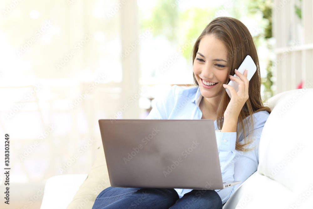 Happy girl working with laptop calling on phone at home Happy girl working with laptop calling on phone at home