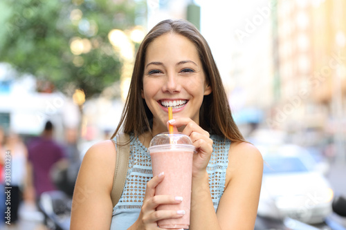 Cuadro en lienzo Happy girl looking at you drinking milkshake in the street