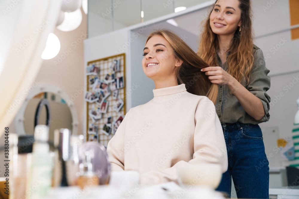 Blonde girl indoors in beauty salon with hairdresser. Blonde girl indoors in beauty salon with hairdresser.