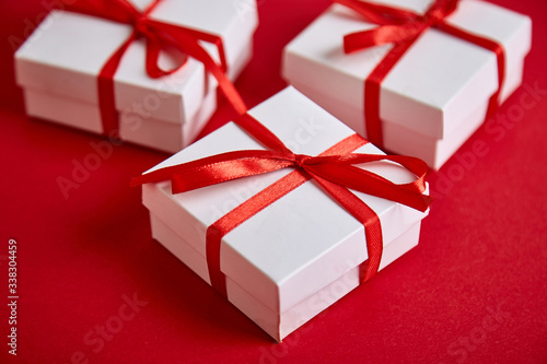 Luxury white gift boxes with red ribbon on red background.