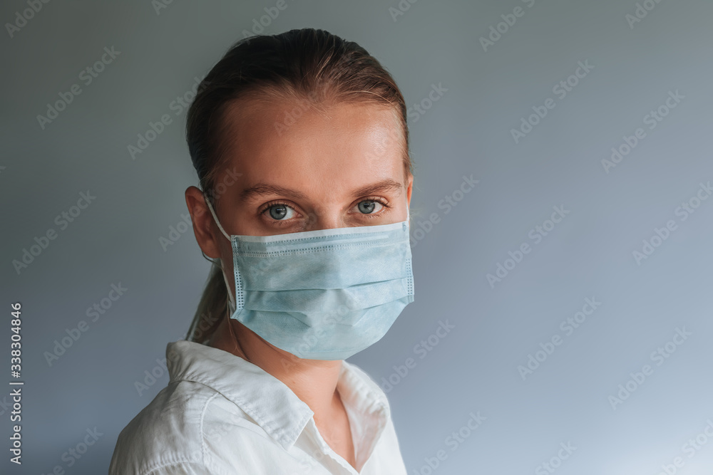 A woman in a medical mask on a light gray background A woman in a medical mask on a light gray background