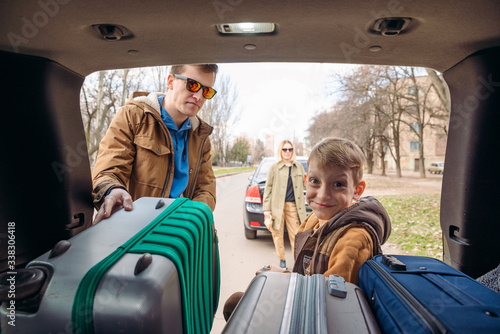 family with kid putting bag in car trunk