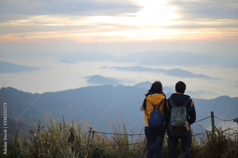 Man and woman standing in the fog and mountain view at Phu Chi Fa National Park, Chiang Rai, Thailand