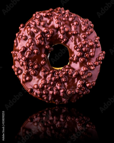 Fototapeta Naklejka Na Ścianę i Meble -  Glazed chocolate donut with nuts on a black background rotated