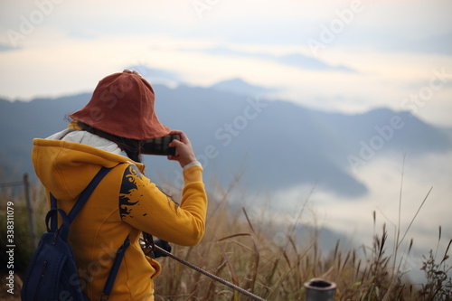A woman standing in the fog and mountain view at Phu Chi Fa National Park, Chiang Rai, Thailand © pantkmutt