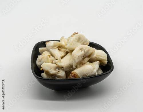 Closed up premium jumbo lump of fresh blue crab meat in small black ceramic bowl isolated on white