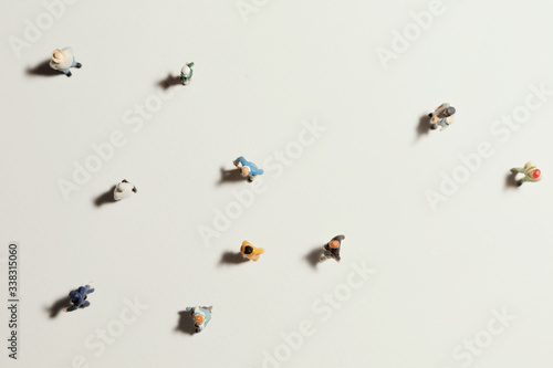 Top view of people (miniature toys) with long shadows keep distance away in public during sunrise or sunset.Social distancing / COVID-19 coronavirus outbreak spreading concept.