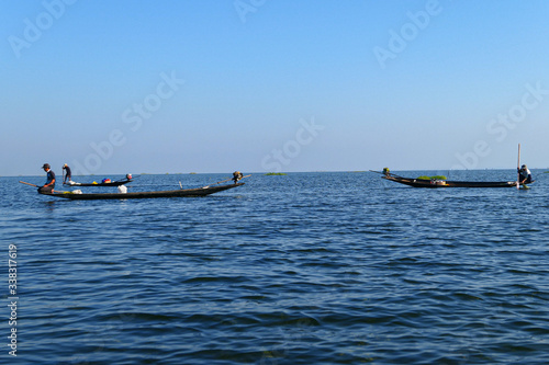 Aisan fisherman on the wooden boat on the lake. Men fishing on the blue river. © find_me_on_map