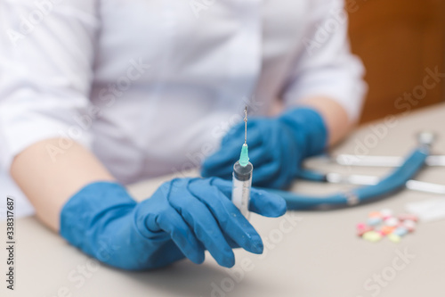 Doctor's hand in a blue medical glove holds a syringe with medicine. Close-up. Colorful medicine on a background. © Вера Дымова