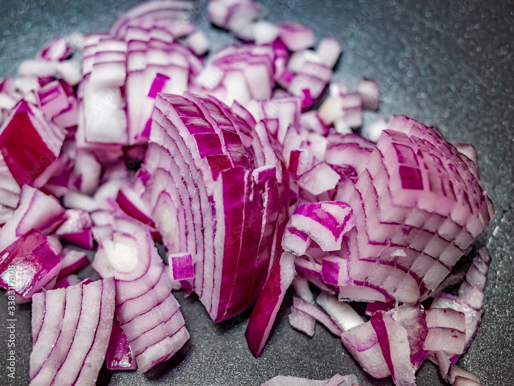 Fototapeta premium Close up and selective focus of sliced red onion (Allium cepa) in a non-stick pan ready for frying off on the hob