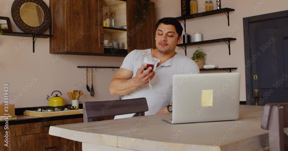 Handsome Hispanic man having a glass of wine during video call with friends or partner. Stay home, quarantine life Handsome Hispanic man having a glass of wine during video call with friends or partner. Stay home, quarantine life