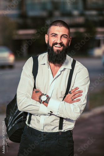 Bearded hipster businessman standing outdoor in office building background