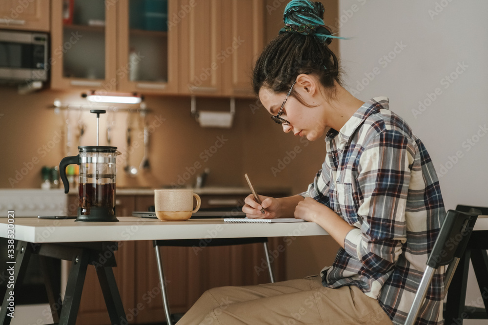 A woman works at home in the kitchen at the dining table. In a relaxed position. A woman works at home in the kitchen at the dining table. In a relaxed position.