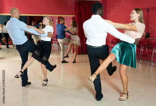 Young positive people dancing vigorous jive movements in dance studio