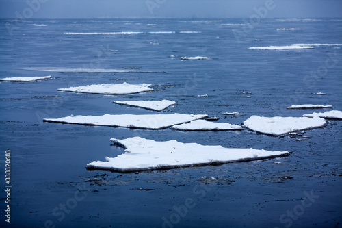 Icebergs in the water. Flat white ice floes floating in the blue sea. © Simon