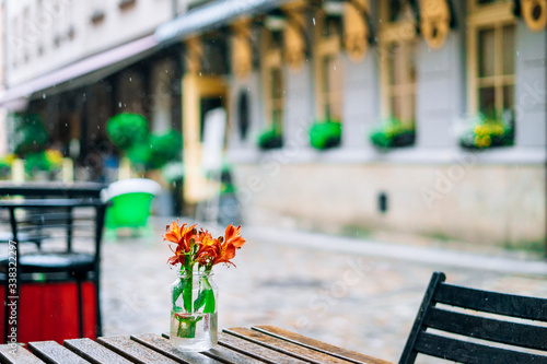 Beautiful alstroemeria in vase on wooden table in summer cafe. Gentle summer bouquet in a glass vase. © chdenisz