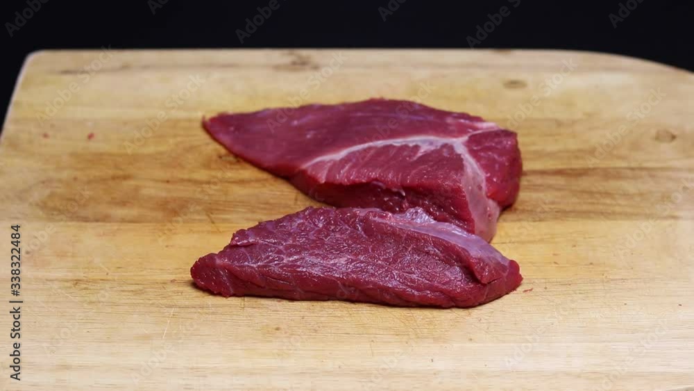 Pieces of raw meat fall on a cutting board. Pieces of raw meat fall on a cutting board.