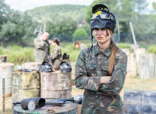 Portrait of young woman in protective helmet with splash in paintball game