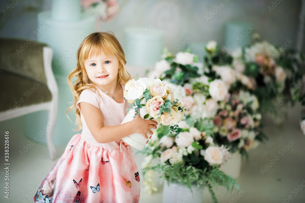 Portrait of little smiling 3 years old blonde girl in pink dress holding gift box with flowers in day time in bright studio. Indoors spring photoshoot of small child. Mothers day Portrait of little smiling 3 years old blonde girl in pink dress holding gift box with flowers in day time in bright studio. Indoors spring photoshoot of small child. Mothers day