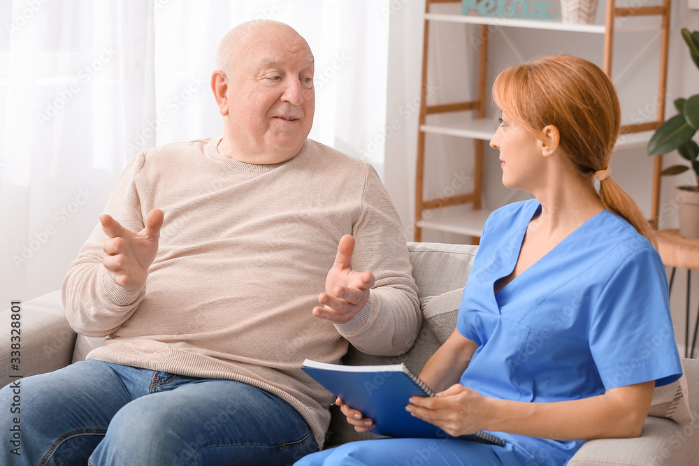 Obraz premium Elderly man suffering from mental disability and caregiver in nursing home