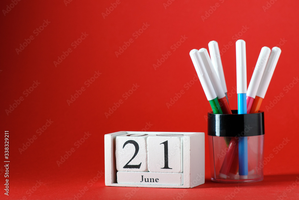 Wooden calendar with the date of June 21, felt-tip pens, on a red background Wooden calendar with the date of June 21, felt-tip pens, on a red background