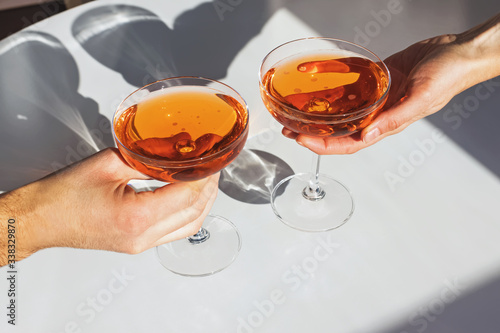 Papier peint Close up view of man and woman hands holding glasses with cocktail of orange col